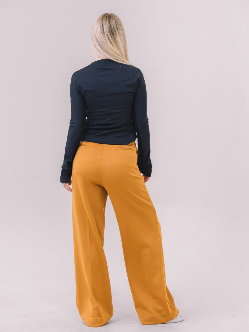 Back view of the Freya Wide-Leg Knit Pants in camel, styled with the navy Ayla Polo Top.